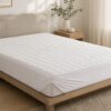 White quilted waterproof mattress protector on a modern bed
