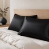 Black satin pillowcases styled on a warm neutral bed
